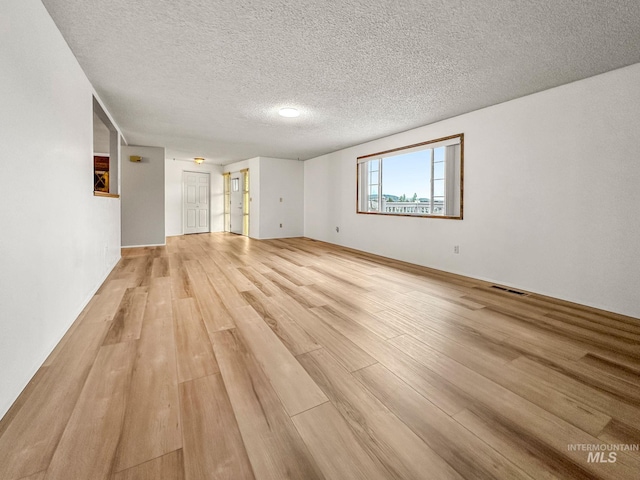 unfurnished room with a textured ceiling and light wood-type flooring