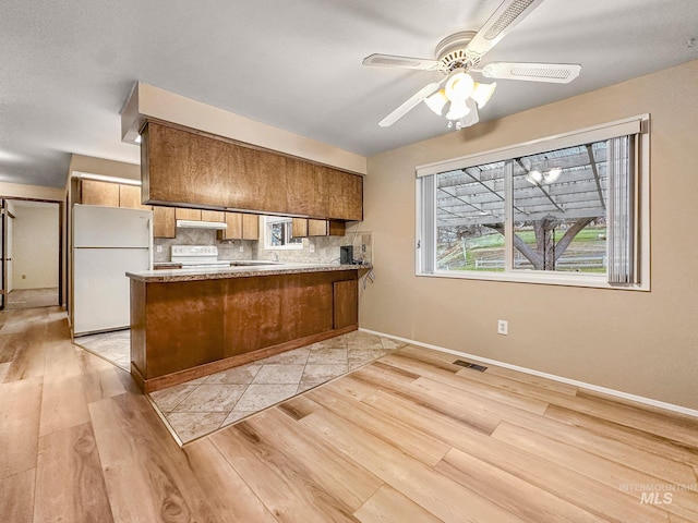 kitchen featuring ceiling fan, kitchen peninsula, light hardwood / wood-style floors, white appliances, and decorative backsplash