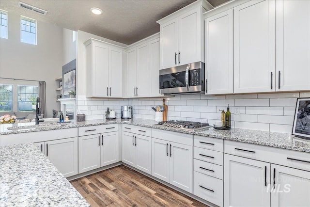 kitchen featuring stainless steel appliances, a sink, white cabinetry, plenty of natural light, and a textured ceiling