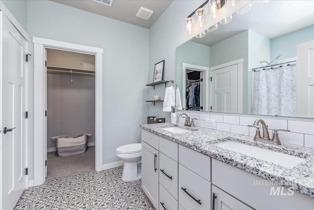 bathroom with toilet, double vanity, baseboards, a walk in closet, and a shower with shower curtain