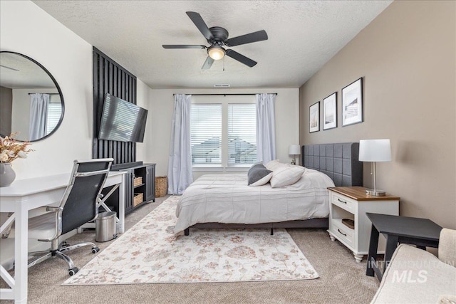 carpeted bedroom with a textured ceiling, a desk, and ceiling fan