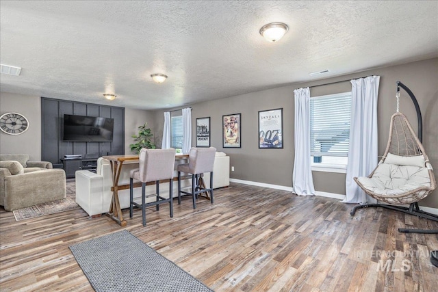 living room with a textured ceiling, wood finished floors, plenty of natural light, and baseboards