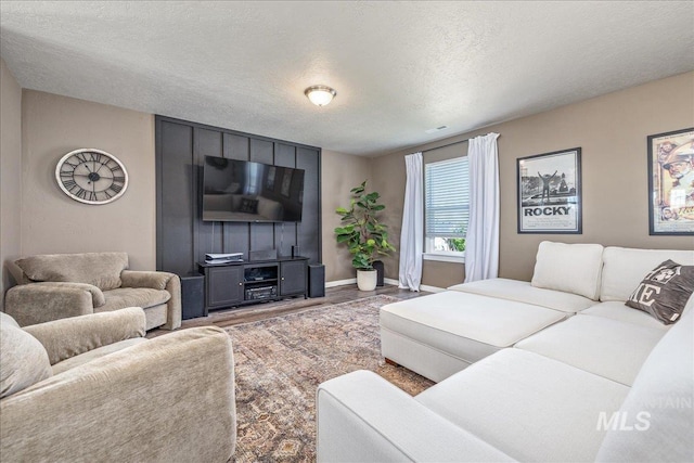living area featuring a textured ceiling, wood finished floors, and baseboards