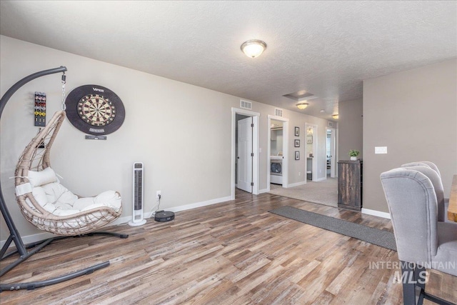unfurnished room with wood finished floors, baseboards, a textured ceiling, and washer / dryer