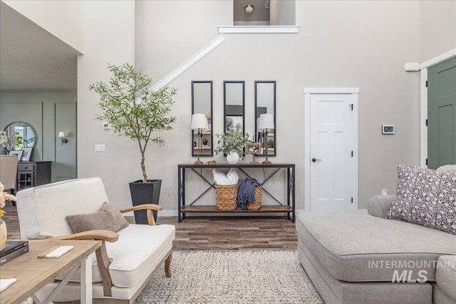 sitting room with a towering ceiling, wood finished floors, and baseboards