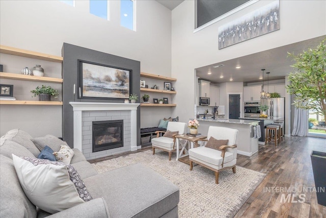 living area with dark wood-style floors, a high ceiling, and a fireplace