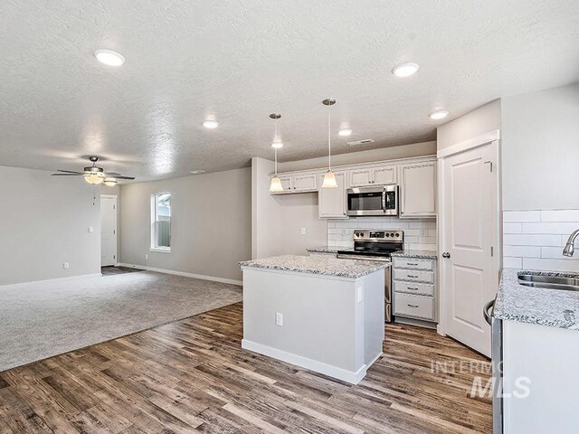 10144 Longtail Dr, Nampa, ID 83687 - kitchen with a center island, a sink, appliances with stainless steel finishes, wood finished floors, and decorative backsplash