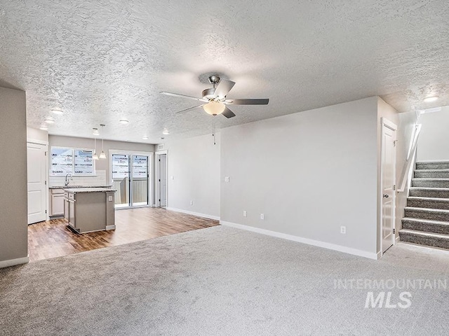 10144 Longtail Dr, Nampa, ID 83687 - unfurnished living room featuring ceiling fan, carpet flooring, a sink, stairs, and baseboards