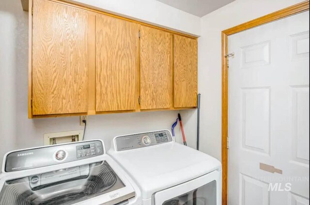 clothes washing area featuring washing machine and dryer and cabinets