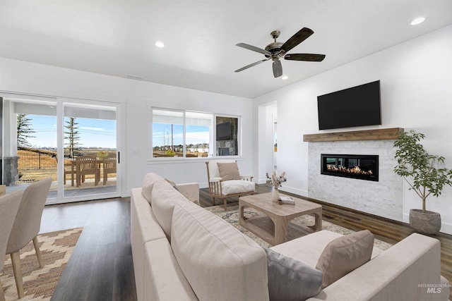 living area featuring a glass covered fireplace, recessed lighting, and wood finished floors