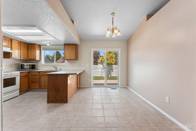 816 W Georgia Ave, Nampa, ID 83686 - kitchen featuring stainless steel microwave, white electric range, under cabinet range hood, a peninsula, and a sink