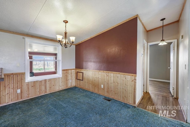 carpeted empty room featuring crown molding, wainscoting, and wooden walls