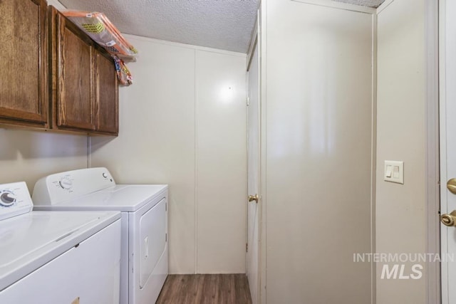 laundry room featuring cabinet space, a textured ceiling, washing machine and dryer, and wood finished floors