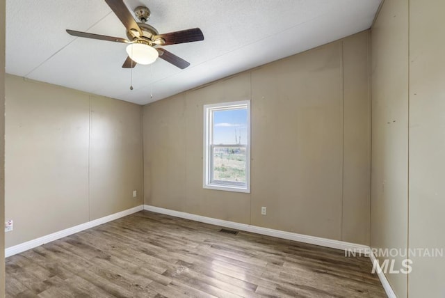 unfurnished room featuring ceiling fan, visible vents, wood finished floors, baseboards, and lofted ceiling