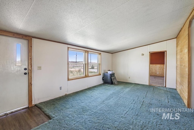 carpeted empty room featuring a wood stove and a textured ceiling