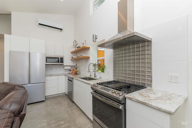 712 E Sheridan, Nampa, ID 83686 - kitchen featuring stainless steel appliances, wall chimney range hood, a wall unit AC, white cabinetry, and backsplash