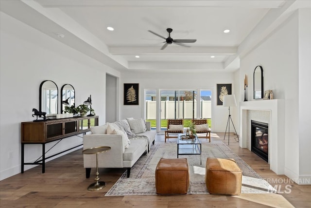 living room with ceiling fan, hardwood / wood-style flooring, and beamed ceiling