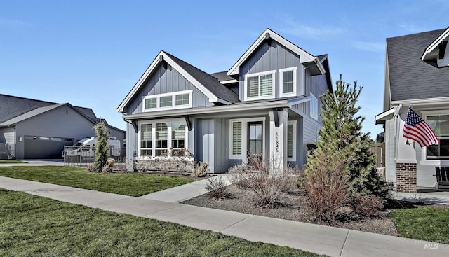 view of front of property featuring a front yard, fence, a porch, a garage, and board and batten siding