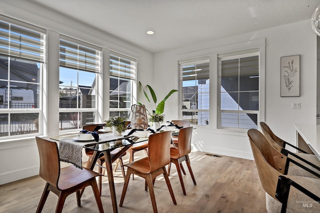 dining area with light wood-style flooring, visible vents, and a wealth of natural light