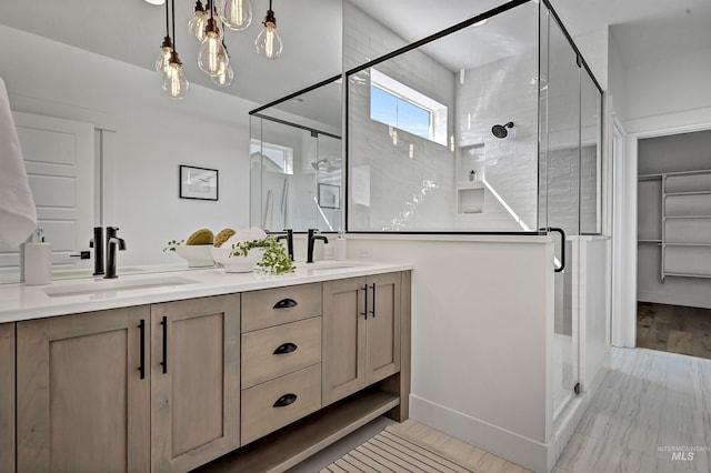 full bathroom featuring double vanity, a stall shower, and a sink