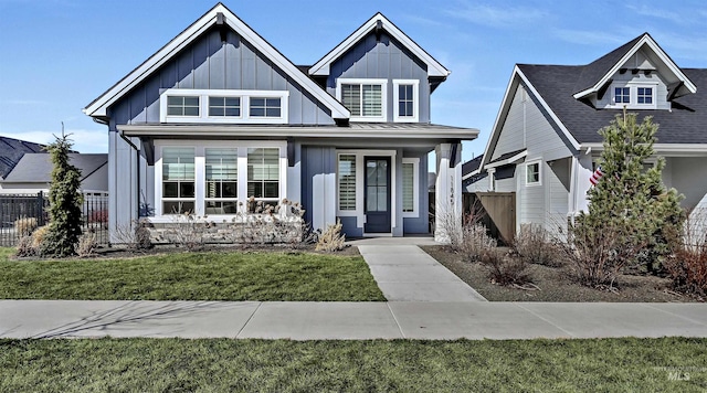 view of front of house with a standing seam roof, a porch, fence, board and batten siding, and a front yard