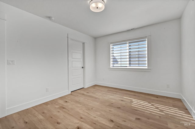 unfurnished room featuring visible vents, baseboards, and wood finished floors