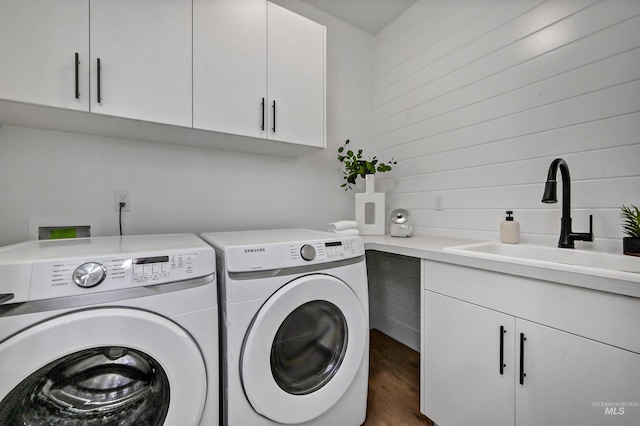 laundry area with a sink, cabinet space, independent washer and dryer, and wood finished floors