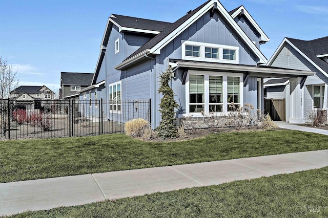 view of front of house with board and batten siding, a front lawn, and fence