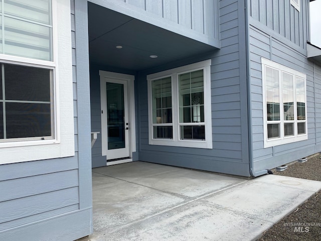 view of exterior entry featuring a patio area and board and batten siding