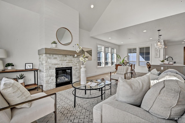 living area featuring high vaulted ceiling, wood finished floors, recessed lighting, a fireplace, and baseboards