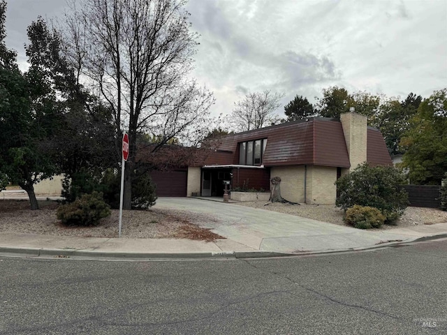 1111 SW 11th Ave, Ontario, OR 97914 - view of front facade featuring concrete driveway, a chimney, mansard roof, and a garage