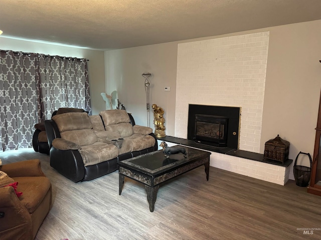 living room with hardwood / wood-style floors, a brick fireplace, and a textured ceiling