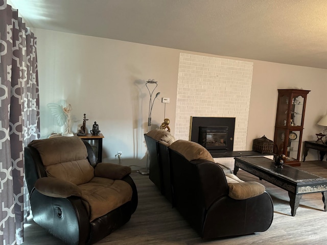 living room with a brick fireplace and wood-type flooring