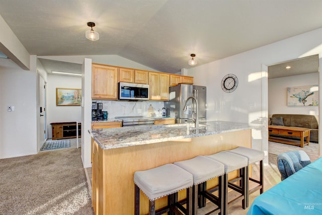 4420 N Ginzel St, Boise, ID 83703 - kitchen featuring a breakfast bar, a center island with sink, light brown cabinets, appliances with stainless steel finishes, and lofted ceiling