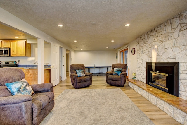 4420 N Ginzel St, Boise, ID 83703 - living room with recessed lighting, a textured ceiling, a stone fireplace, and light wood finished floors
