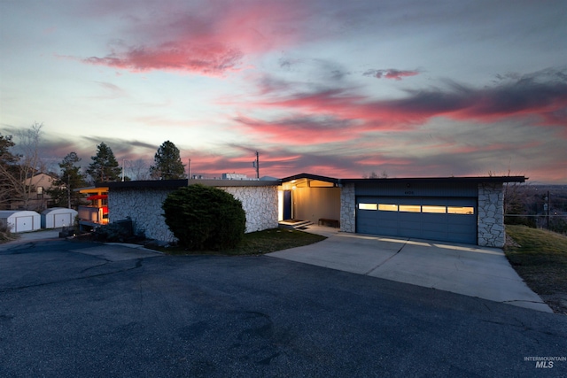 4420 N Ginzel St, Boise, ID 83703 - view of front facade featuring driveway, a shed, an attached garage, an outdoor structure, and stone siding