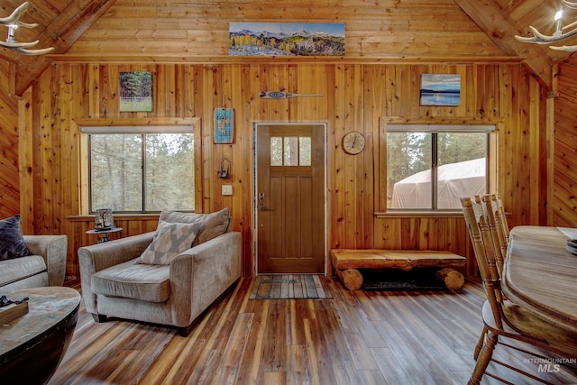 living area with vaulted ceiling with beams, wooden ceiling, wooden walls, and wood-type flooring