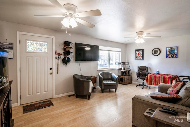 living room with light wood-style floors, ceiling fan, and baseboards