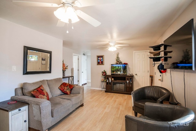 living area featuring light wood-style floors, baseboards, and a ceiling fan