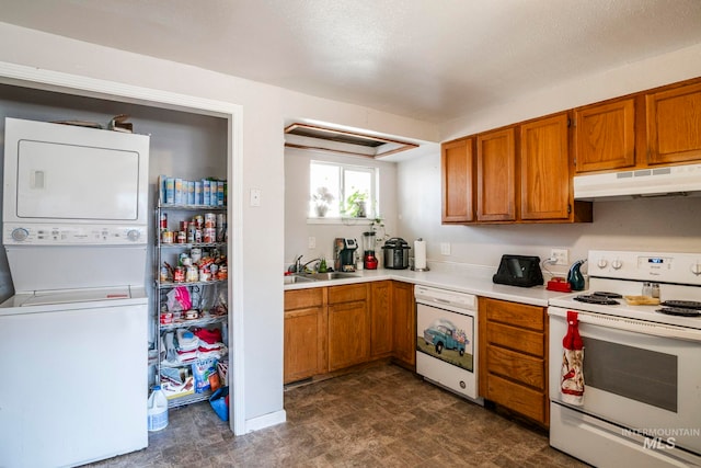 kitchen featuring white appliances, stacked washer / dryer, light countertops, under cabinet range hood, and a sink