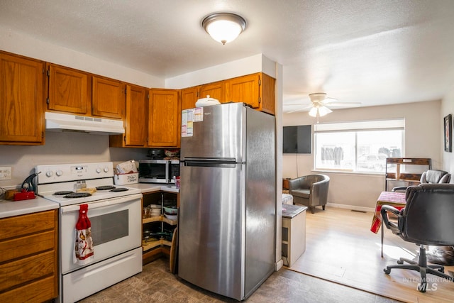 kitchen with under cabinet range hood, stainless steel appliances, open floor plan, light countertops, and brown cabinetry