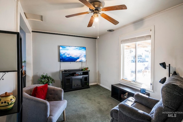 living area with carpet flooring, crown molding, baseboards, and ceiling fan