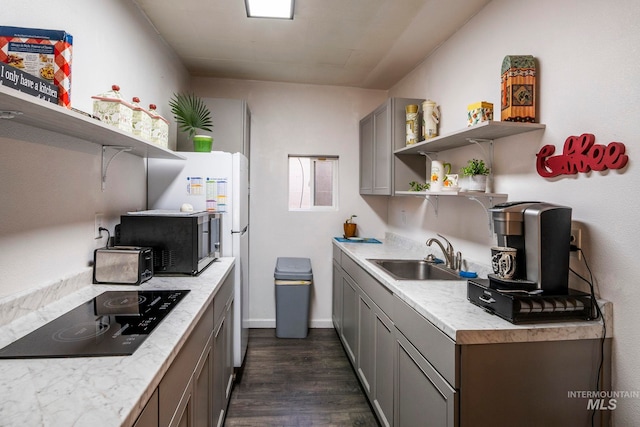 kitchen featuring light countertops, a sink, black appliances, and open shelves