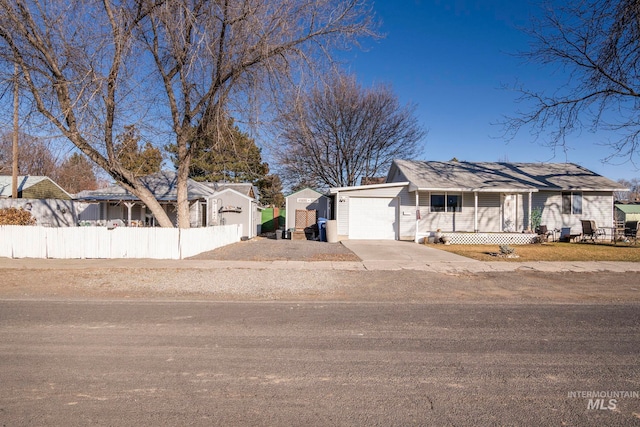 ranch-style home with covered porch, concrete driveway, fence, and a garage