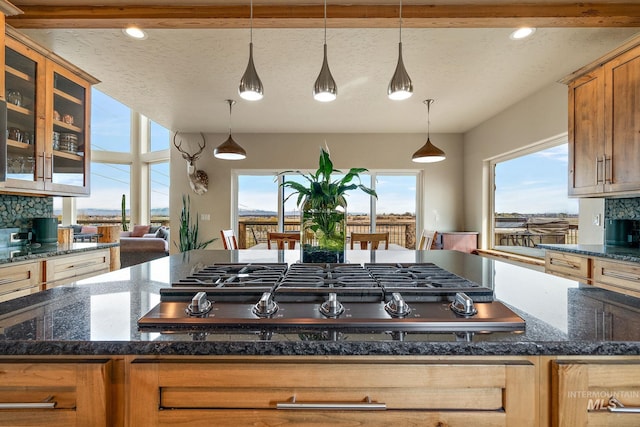 13331 Peaceful Way, Nampa, ID 83686 - kitchen with pendant lighting, stainless steel gas cooktop, glass insert cabinets, a textured ceiling, and tasteful backsplash