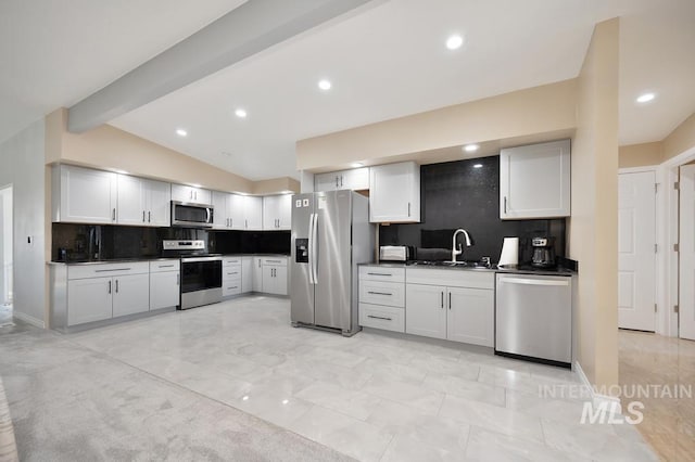 kitchen with appliances with stainless steel finishes, lofted ceiling with beams, white cabinetry, and sink