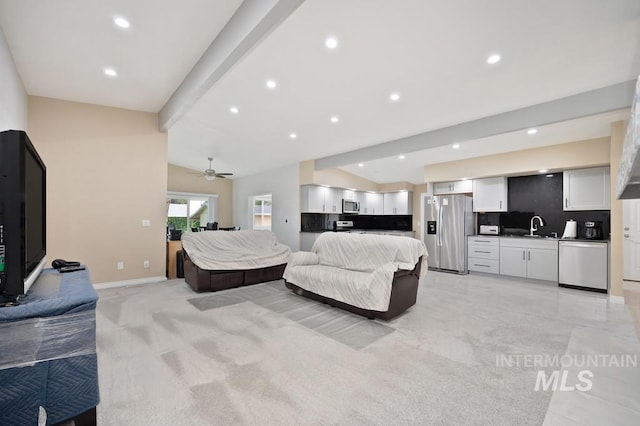 living room with vaulted ceiling with beams, ceiling fan, light colored carpet, and sink