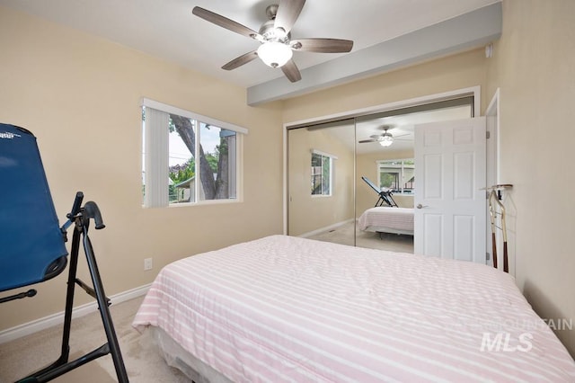 bedroom with ceiling fan, light colored carpet, and a closet