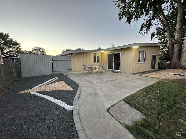 back house at dusk with a patio area