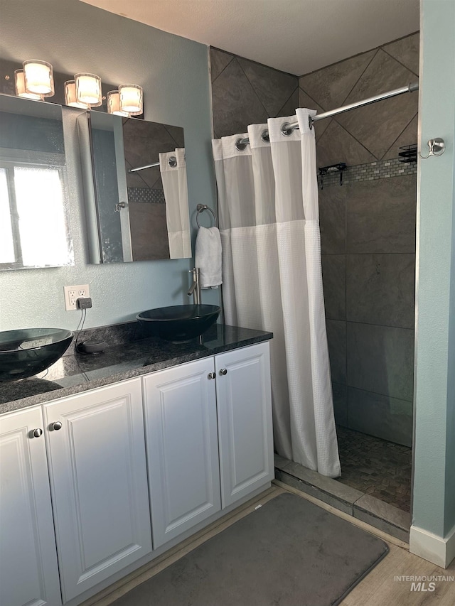 2405 23rd St, Clarkston, WA 99403 - bathroom featuring a tile shower, double vanity, and wood finished floors